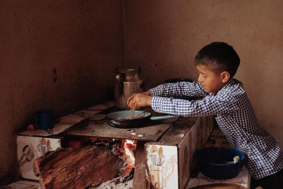 Tomás, nine, making eggs with tomatoes at his home in Quiche district, Guatemala