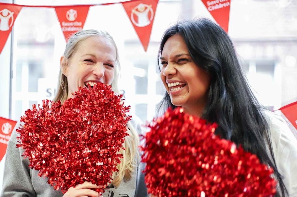 Two Shelter For Kids Dubai, UAE employees share a laugh together whilst holding red hearts for supporter week 2019